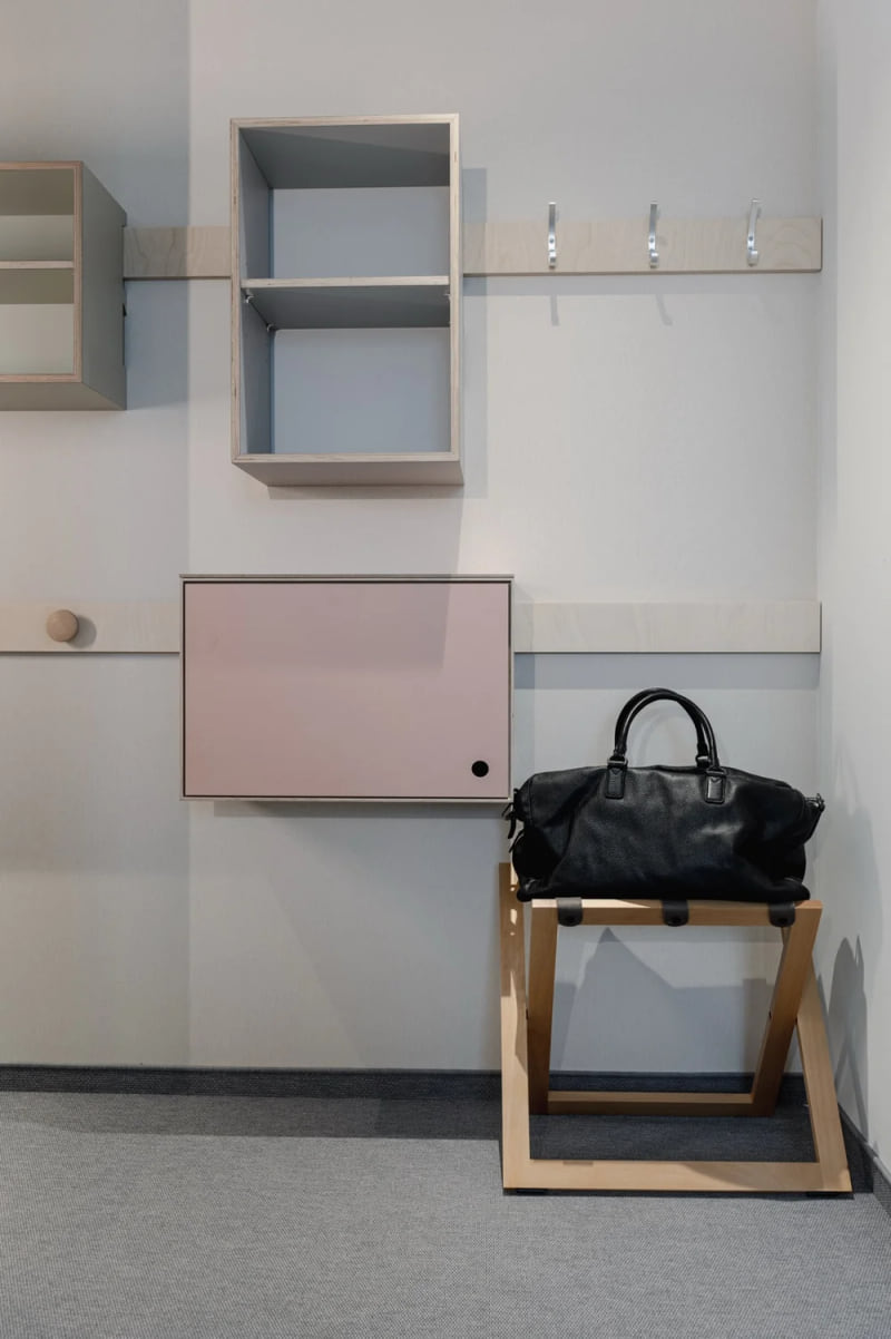 Offener Eingangsbereich im Hotel baltica Hamburg Altona mit Garderobe, offenen Regalen, Hakenleiste und schwarzer Reisetasche auf einem Holzgestell.